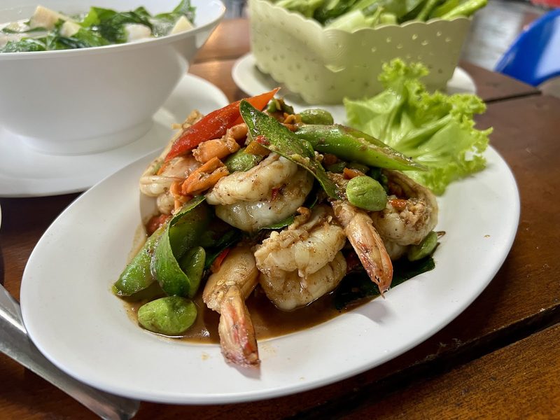 กุ้งผัดสะตอ พริก และกระเทียม บนจานขาวรองผักกาด