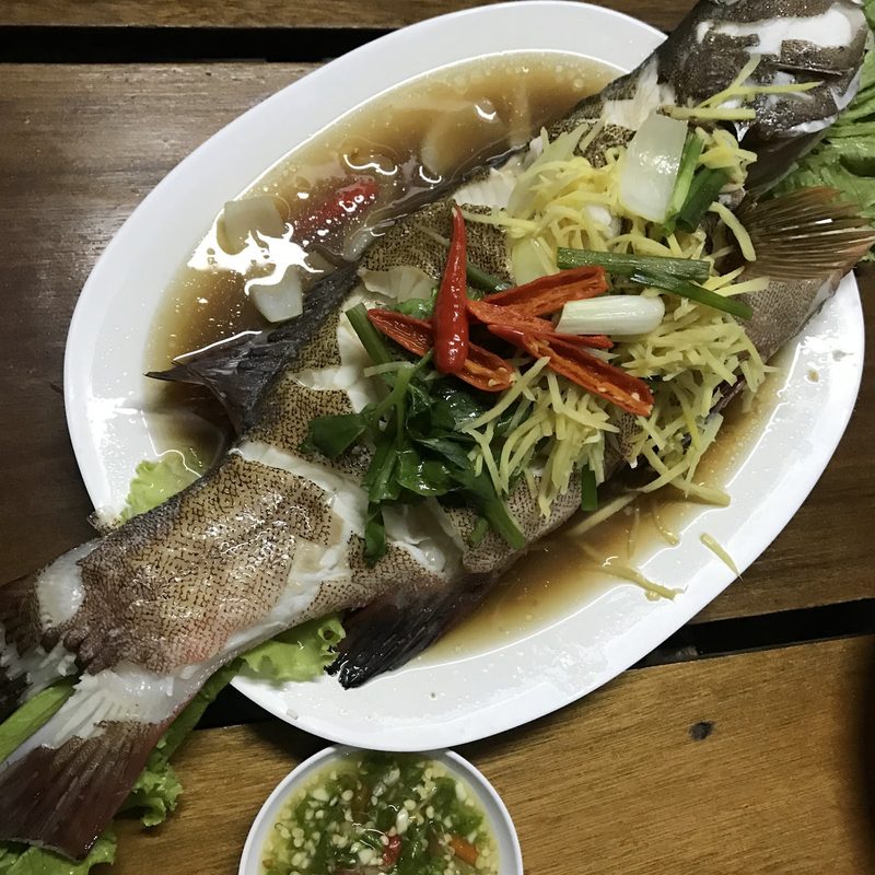 ปลานึ่งทั้งตัว โรยพริก มะนาว และผักสมุนไพร