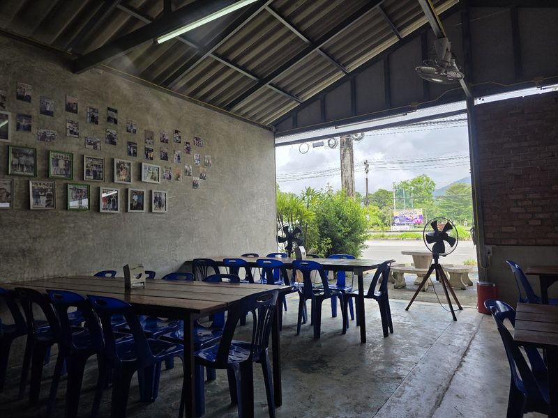 ในร้าน โต๊ะไม้สีเข้ม เก้าอี้สีน้ำเงิน และผนังติดรูปเต็มแถว