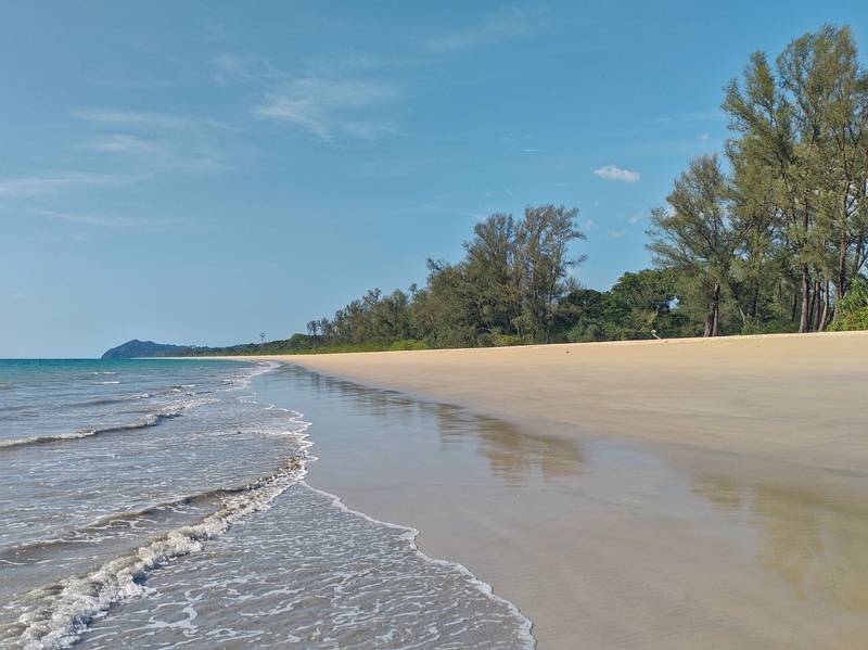 หาดทรายยาวโค้งไปตามแนวสนทะเล คลื่นซัดเข้าฝั่งเบา ๆ